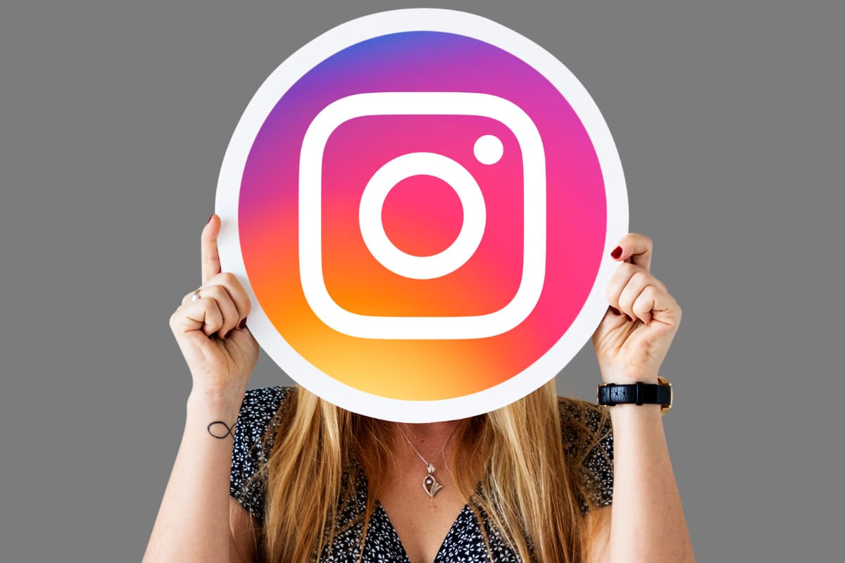 imagem de mulher segurando a logo do Instagram na altura do rosto, cobrindo esse último