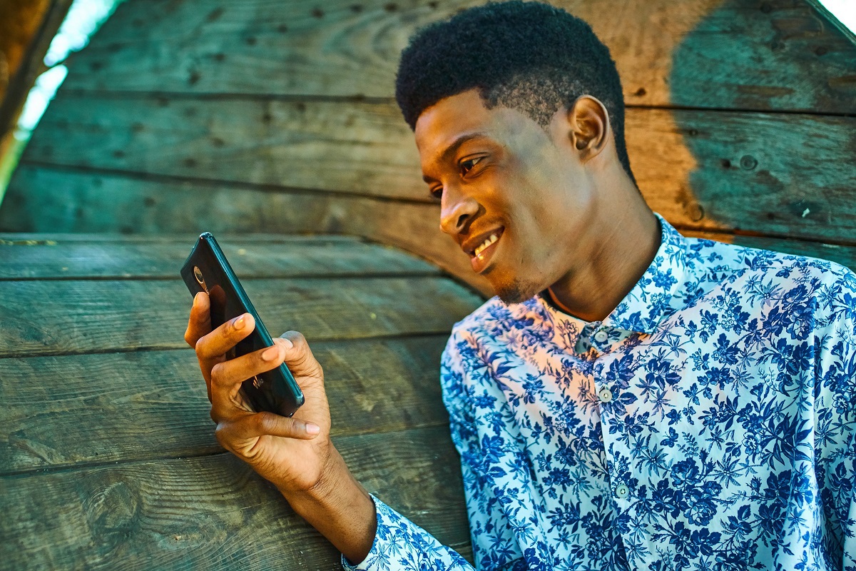 homem negro sorrindo com o celular na mão