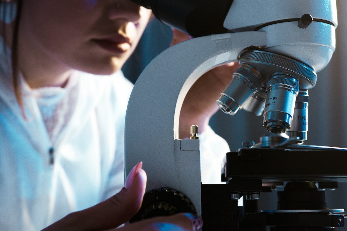 pessoa usando um microscópio em ambiente laboratorial