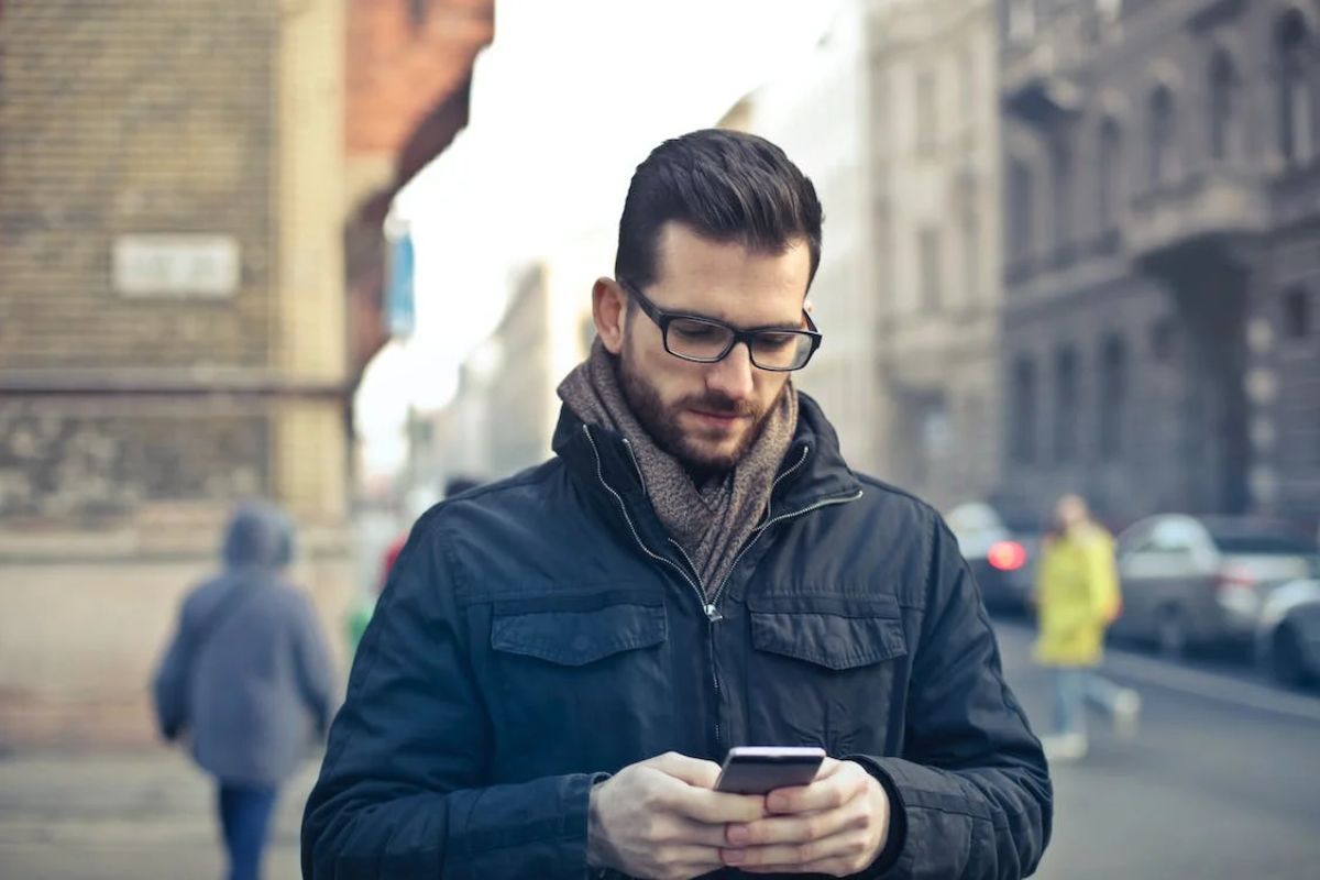 Homem na rua usando smartphone concentrado