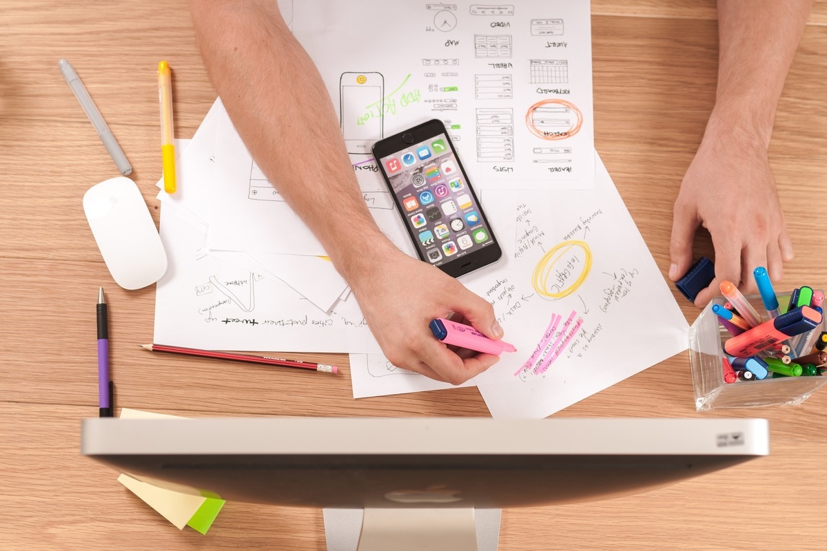 Homem usando computador sobre mesa de madeira e folhas de papel planejando estratégia com diferentes Tipos de marketing e smartphone