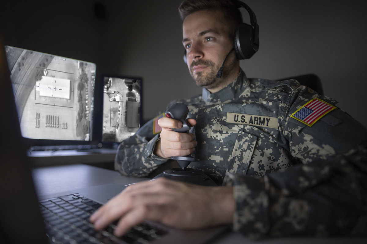 Soldado dentro de ambiente com computadores e segurando objeto de comunicação, outro exemplo do avanço da Tecnologia militar