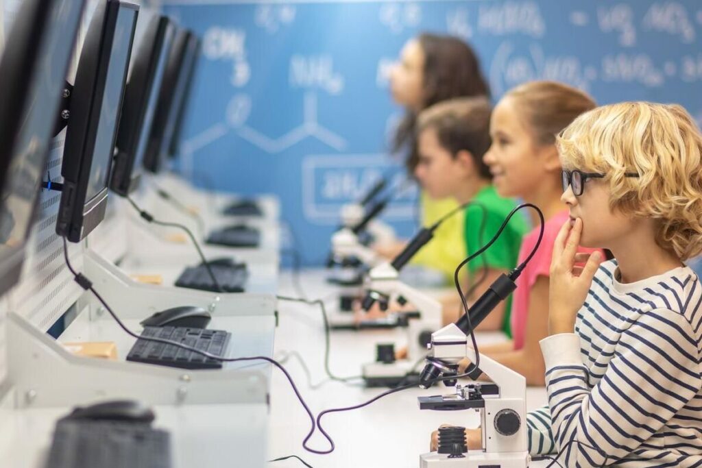 tecnologia na educação: a imagem mostra algumas crianças usando computadores em sala de aula. 